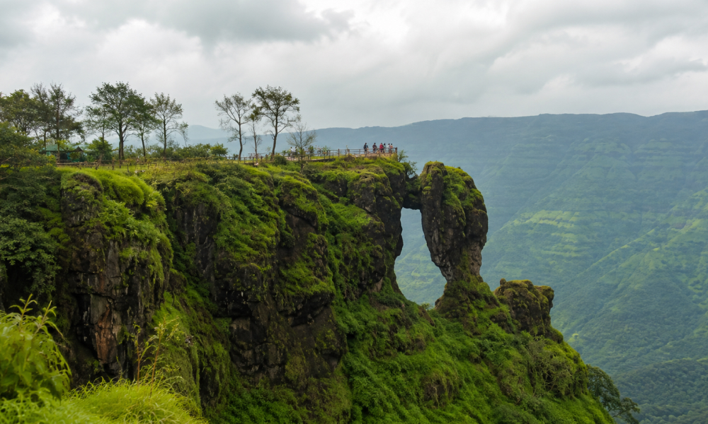 Friends at a green cliffside viewpoint overlooking the misty Western Ghats in Mahabaleshwar